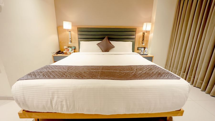 An image of a bedroom with double size bed and bedside table on either side - Pride Resort Ambaji